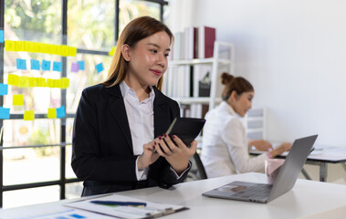 Happy Asian businesswoman working on financial documents in the office. Female accountant doing accounting work and auditing.