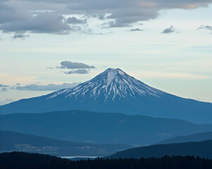 Majestic mountain peak covered in snow against a soft sky with layered mountain range and wispy clouds creating a serene and captivating scene