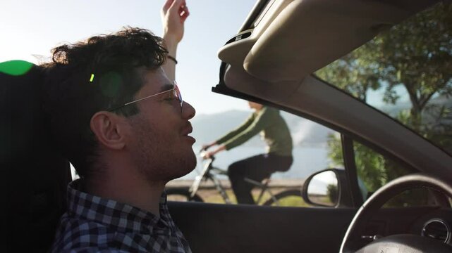 Happy and contented man rides an electric car along the shore at sunset. Concept of travel, business and delivery of goods. Sunset ride. Delivery of goods to door by car.