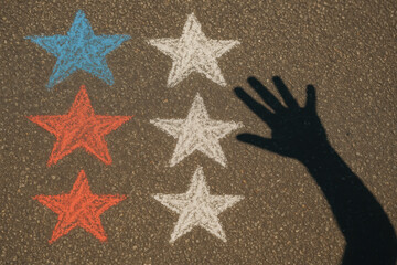 Shadow of hand over colorful stars on asphalt, suggesting creativity and imagination in art