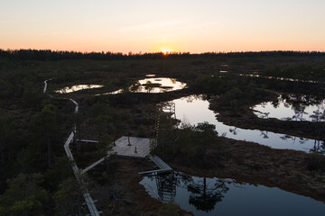 Obraz premium Estonian wilderness at twilight: aerial shot of Seli bog with boardwalk, viewing tower, and water reflections.