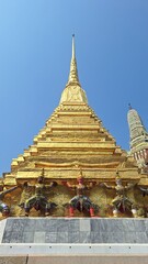Naklejka premium Golden Spire Pagoda with Guardian Giants, Wat Phra Kaew, Thailand