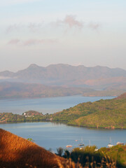 Scenic morning view from Mount Tapyas overlooking calm sea waters, green hills, and anchored boats...