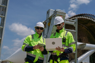 Maintenance engineer team standing at windmills at wind turbine farm. Group of people wear safety...