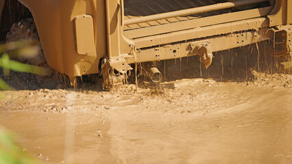 Close-up of the rear of a muddy off-road vehicle stuck in a muddy puddle. Racing in extreme conditions.