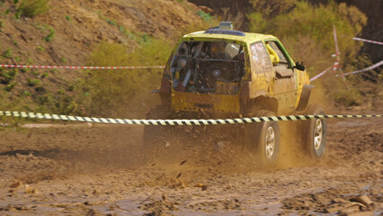 SUV racing on the mud. A yellow off-road vehicle is racing on a muddy highway. The car raises a cloud of splashes and mud, racing through difficult terrain.