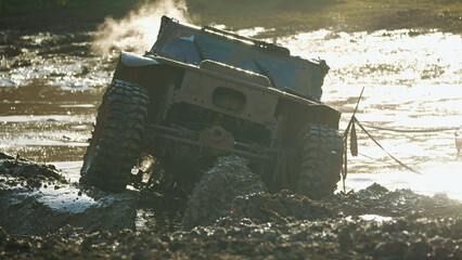 The off-road vehicle is stuck in a muddy ditch. Steam is rising from the engine. Dirty powerful SUV in a muddy puddle. Epic moment of extreme competition.