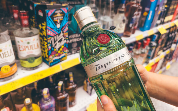 Guayaquil, Ecuador &ndash; April 22, 2025: Person holding a bottle of imported Tanqueray gin, featured on a supermarket shelf amid a growing trend for premium spirits.