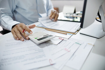 Accountants working in office use calculators to calculate business costs, profits and tax