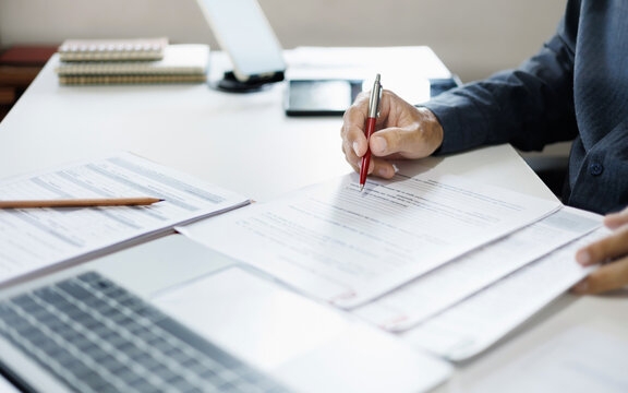 asian businessman working on desk reading and checking financial documents and business contract to make new business plan