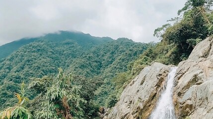 Obraz premium Lush green mountains backdrop a cascading waterfall