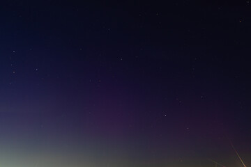 Naklejka premium A clear night sky filled with visible stars gradually fades into a soft horizon glow, creating a tranquil and minimal celestial scene copy space present.