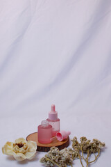 This high-angle, close-up shot showcases two frosted pink glass dropper bottles arranged on a natural wooden coaster.