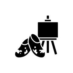 Black Icon of Paint-Spattered Shoes Beside Easel - Artist Lifestyle