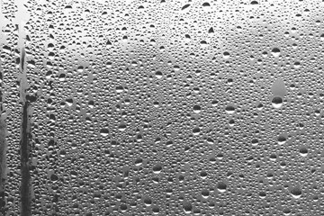 Rain drops on window glass. Natural Pattern of raindrops. Water droplets on a gray background.