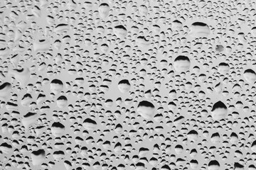 Rain drops on window glass. Natural Pattern of raindrops. Water droplets on a gray background.