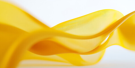 flowing yellow silk fabric creates sense of elegance and fluidity against soft background, capturing essence of movement and grace