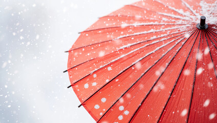 red umbrella is covered in falling snowflakes against white background, creating striking contrast and serene winter scene