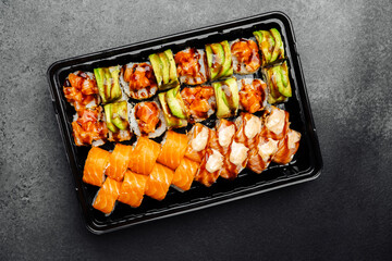 Sushi platter featuring various rolls and sashimi on a dark background