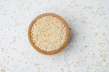 Natural sesame seeds placed in a wooden bowl on a light surface