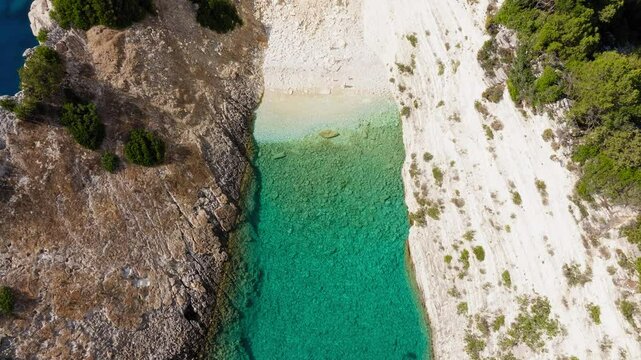 Aerial reveal of rock cliffs and turquoise sea at Hulla Beach, Ithaca Island