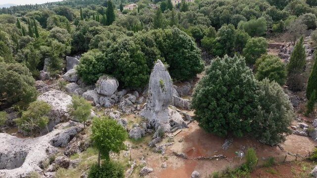 Backwards reveal drone shot of Monolith Araklis in the village of Anogi in Ithaca island, Greece on a sunny day