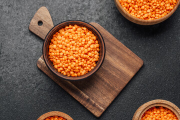 Colorful orange lentils in wooden bowls placed on a dark kitchen surface