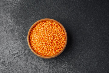 Bright orange lentils in a wooden bowl on a dark background in a kitchen setting