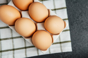 Eggs arranged neatly in a white carton on a checkered cloth