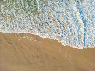 Aerial view of waves lapping the sandy beach