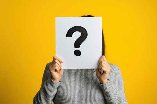 A woman holds a paper with a question mark in front of her face