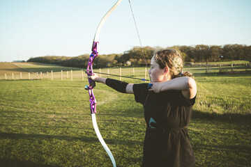 Teen age archer holding bow and arrow, training