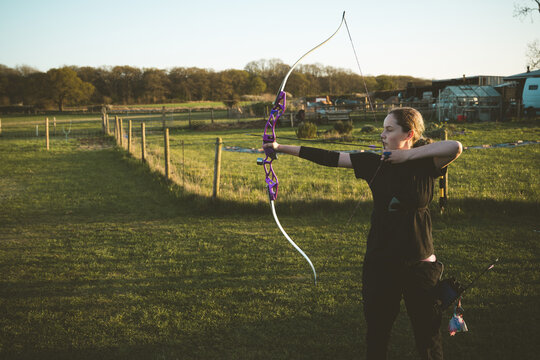 Teen age girl archer holding bow and arrow, training
