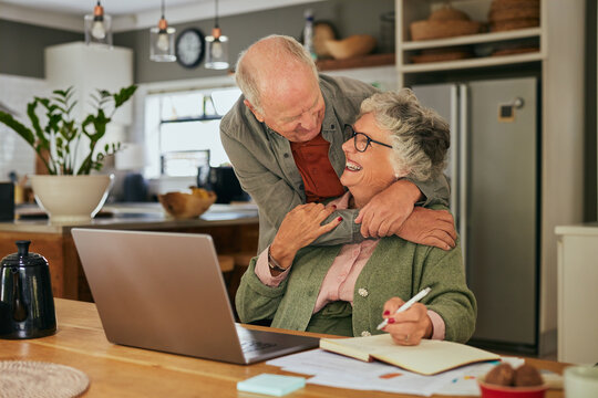 Old man embracing his wife while working on laptop - Powered by Adobe