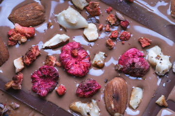 Handmade chocolate close-up. Assorted chocolate with almonds, freeze-dried raspberries and strawberries. . Background for using banners and menus