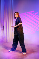 Dancer showcases unique choreography in a dimly lit studio with dramatic lighting effects in the...