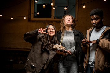 Friends celebrating with a cake in a cozy, dimly lit setting during an evening gathering