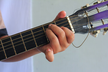 A hand pressing strings on a guitar fretboard, showcasing finger placement and technique in detail. E Major chord