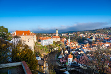 Obraz premium Panoramic view of Cesky Krumlov, showcasing the UNESCO-listed historic center surrounded by the Vltava River in a meander. A sunny autumn day highlights the town's charm.