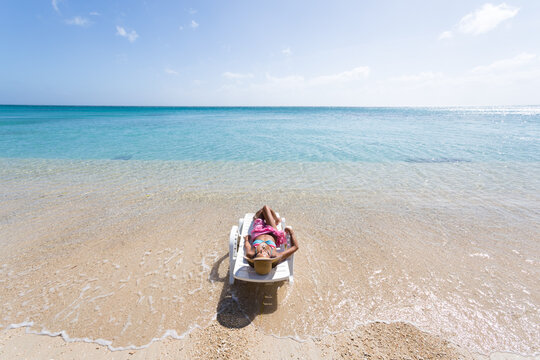 Woman laying down on sunchair, on a beach in summer