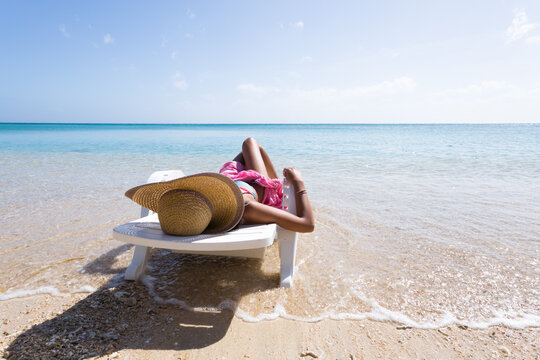 Woman laying down on sunchair, on a beach in summer