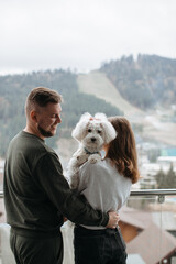 Couple embracing on balcony with their dog, enjoying mountain view