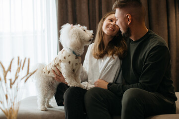 Couple relaxing on sofa with their dog in cozy hotel room