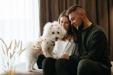 Happy couple cuddling with their dog in hotel room