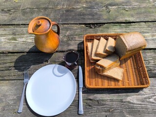 The freshest, warm bread lying next to a white plate on an antique table.