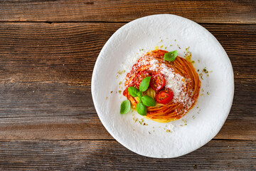 Spaghetti marinara - pasta with tomato sauce, parmesan cheese and basil leaves on wooden table	