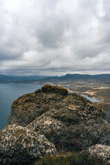 Scenic view from a rocky outcrop overlooking a coastal landscape under cloudy skies