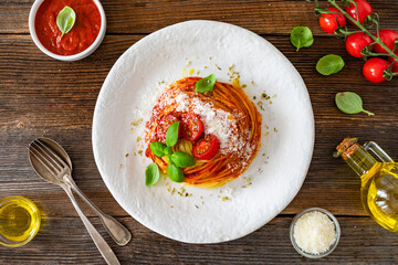 Spaghetti marinara - pasta with tomato sauce, parmesan cheese and basil leaves on wooden table	