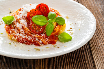 Spaghetti marinara - pasta with tomato sauce, parmesan cheese and basil leaves on wooden table	