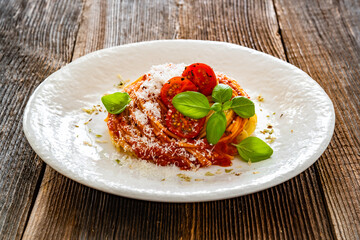 Spaghetti marinara - pasta with tomato sauce, parmesan cheese and basil leaves on wooden table	